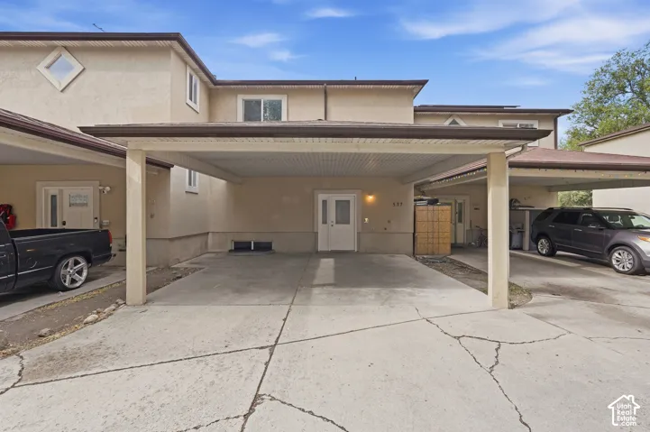 Exterior featuring stucco finish, diamond-shaped window, and a covered carport
