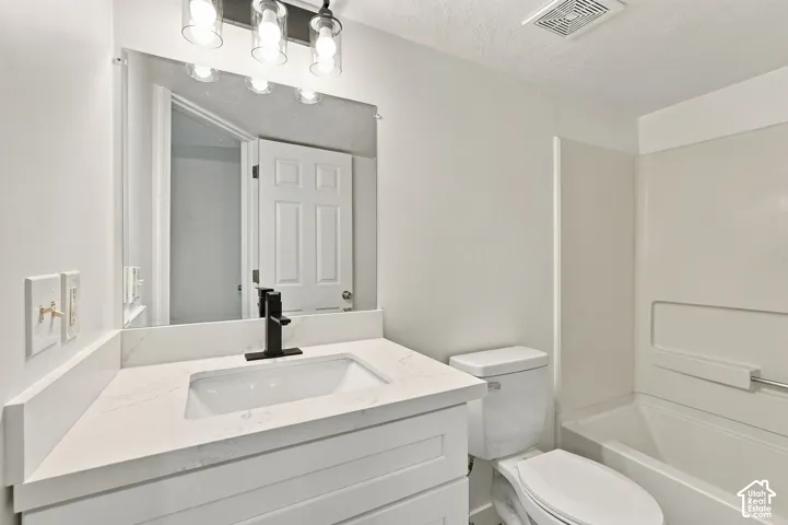 White vanity with a rectangular sink, matte black faucet, and stone-finish countertop