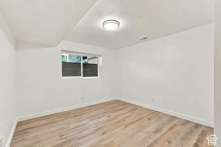 Wood-finish flooring, white walls, and a flush-mount ceiling light
