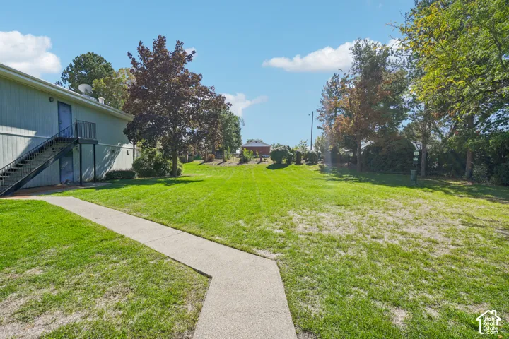 Expansive lawn area with mature trees and a concrete pathway