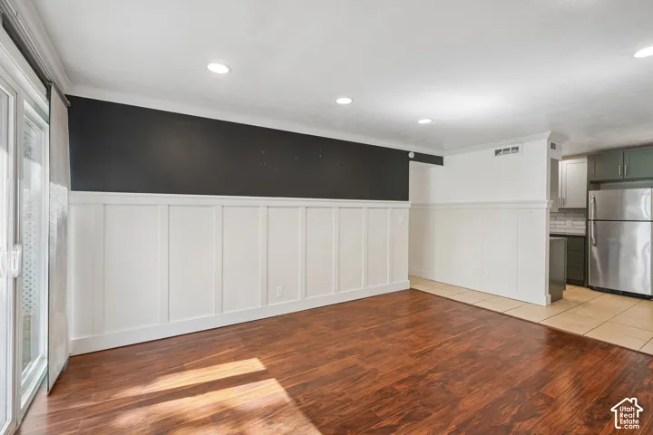 Wood-finish flooring, recessed lighting, board and batten wall detailing, sliding glass door, and a stainless steel refrigerator