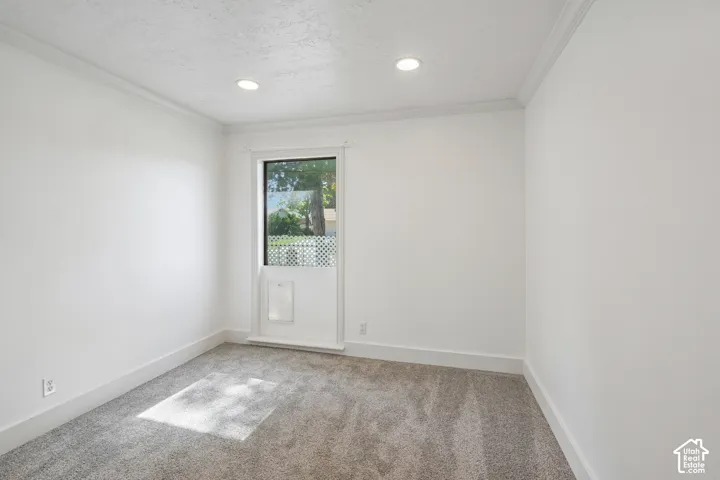 Recessed lighting, crown molding, light gray carpet, and white trim