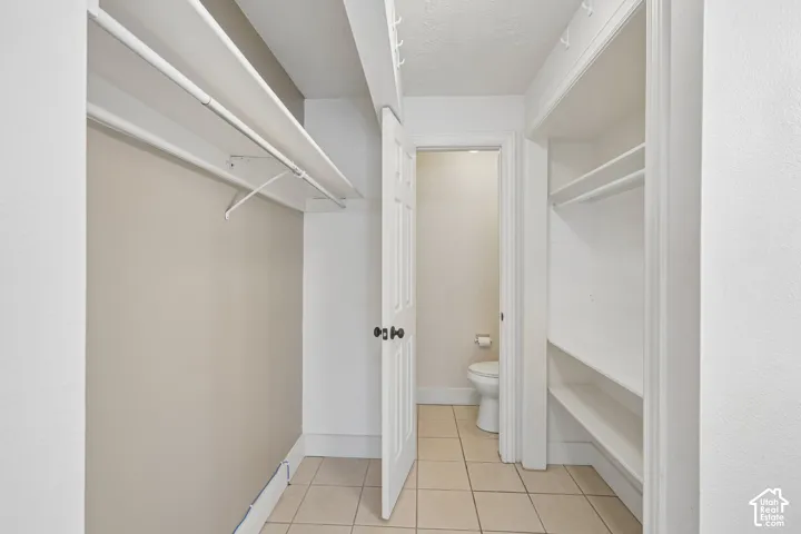 Dual integrated closet rods, built-in shelving, tiled flooring, and a solid core interior door with dark hardware