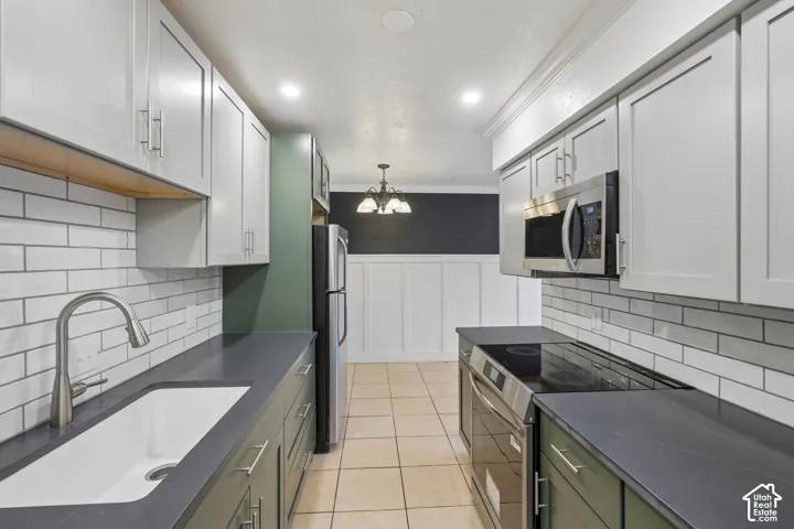 Kitchen featuring light cabinetry, stainless steel appliances, a tile backsplash, and a large single basin sink