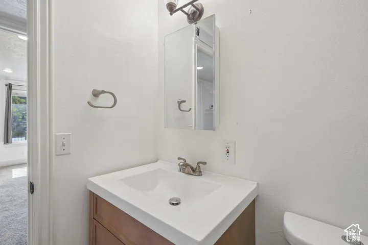 Integrated vanity with a white countertop and basin, wood-finish cabinetry, and brushed nickel fixtures