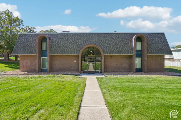 Brick exterior with an arched entryway and dark shingle roof