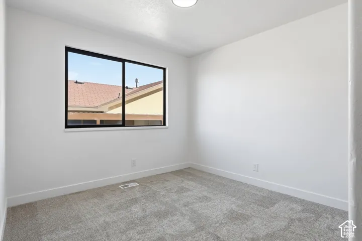 Bedroom featuring neutral wall paint, gray carpet flooring, a black paneled door, and a dedicated closet space with shelving