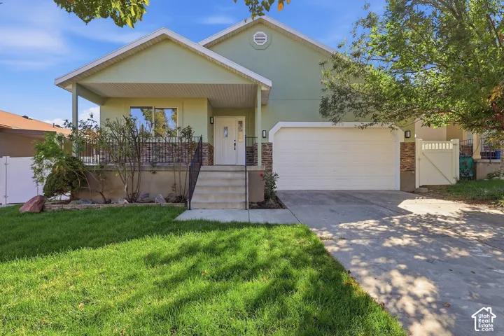 Rambler with stone accent siding, covered entry porch, concrete driveway, attached garage, and a lush lawn