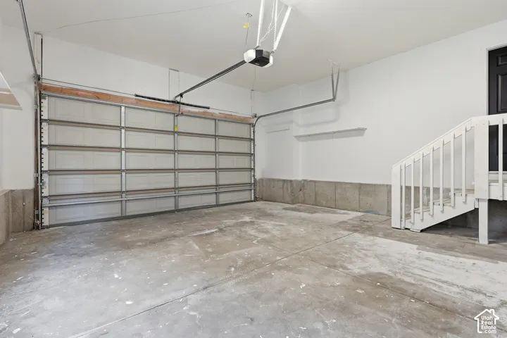 2-Car Garage featuring a sectional garage door, concrete flooring, and white painted walls