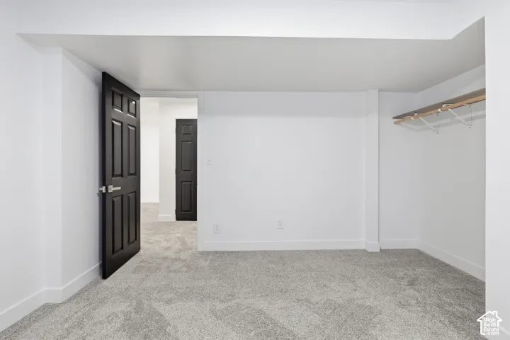 Bedroom featuring neutral wall paint, gray carpet flooring, a black paneled door, and a dedicated closet space with shelving