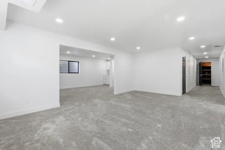 Spacious basement featuring gray carpeting, recessed lighting, and white walls