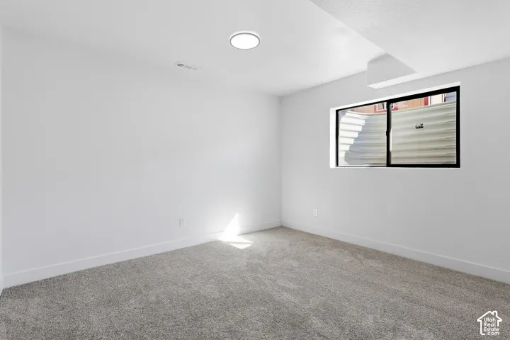 Bedroom featuring neutral wall paint, gray carpet flooring, a black paneled door, and a dedicated closet space with shelving