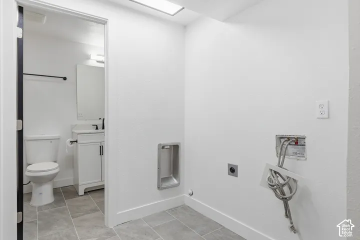 White vanity with a single basin sink, matte black fixtures, and a large wall-mounted mirror. Laundry Room.