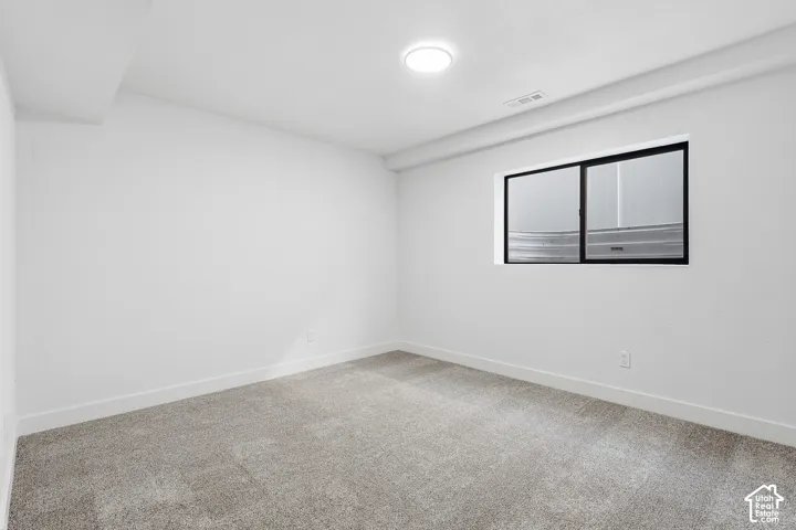 Bedroom featuring neutral wall paint, gray carpet flooring, a black paneled door, and a dedicated closet space with shelving