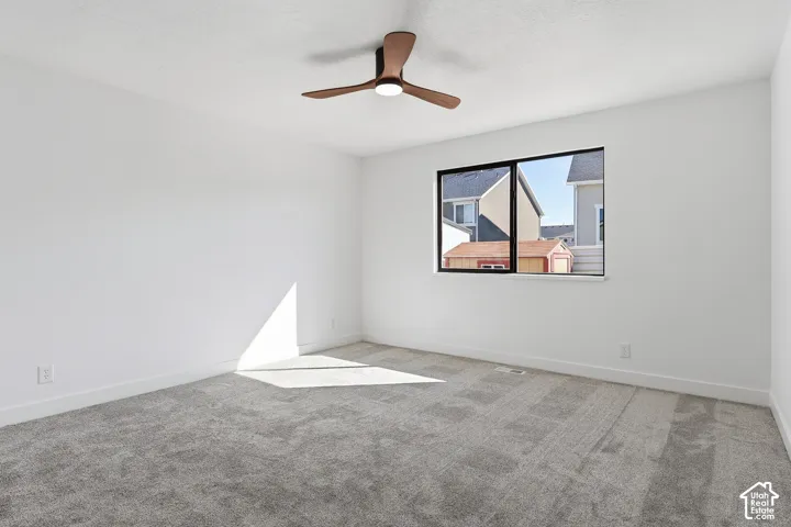Bedroom featuring neutral wall paint, gray carpet flooring, a black paneled door, ceiling fan, and a dedicated closet space with shelving