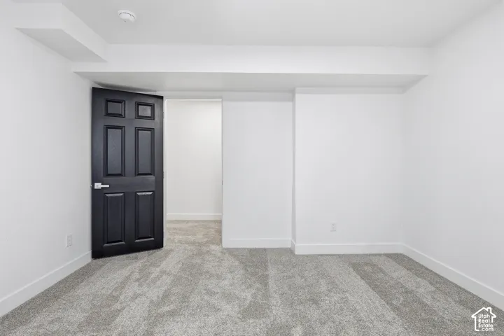 Bedroom featuring neutral wall paint, gray carpet flooring, a black paneled door, and a dedicated closet space with shelving