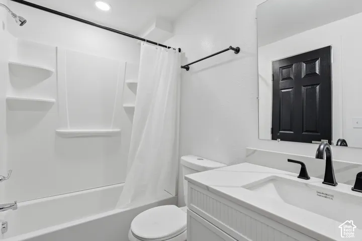 White vanity with a single basin sink, matte black fixtures, and a large wall-mounted mirror