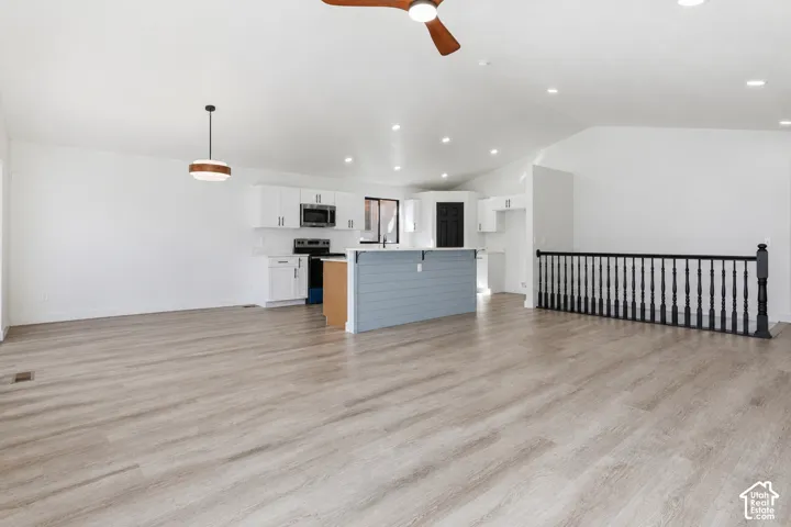 Vaulted ceiling with a ceiling fan, recessed lighting, and LVP-finish flooring throughout