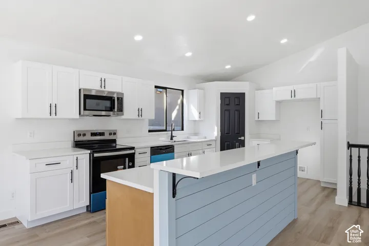 Vaulted ceiling, recessed lighting, LVP-finish flooring, island with light countertop, and white cabinetry. Brand new appliances.