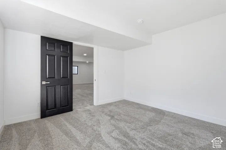Bedroom featuring neutral wall paint, gray carpet flooring, a black paneled door, and a dedicated closet space with shelving