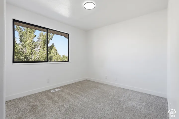 Bedroom featuring neutral wall paint, gray carpet flooring, a black paneled door, and a dedicated closet space with shelving