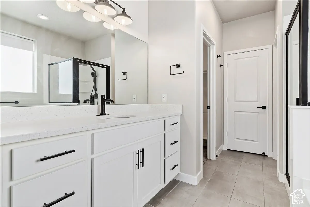 Double vanity with a white countertop and integrated sink, matte black faucet, and white cabinetry with matte black hardware