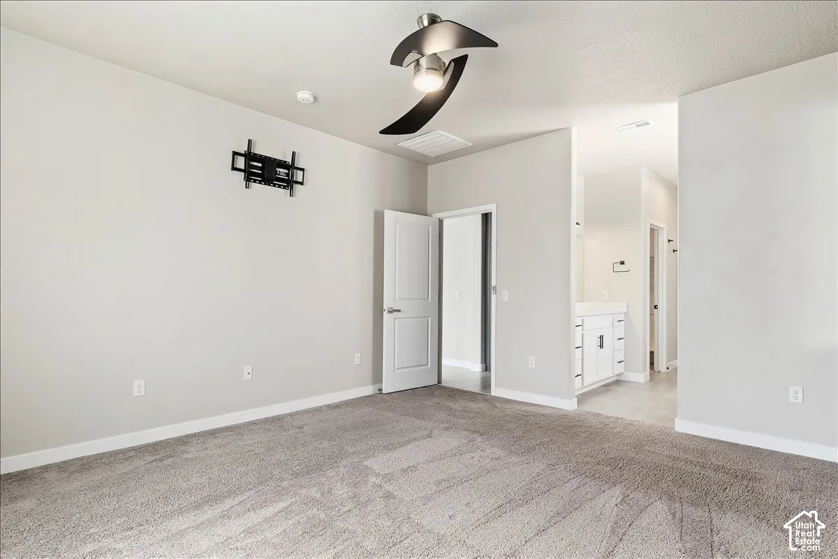 Neutral wall color, ceiling fan, carpet flooring, flat panel interior doors, and a bathroom vanity with shaker-style cabinetry