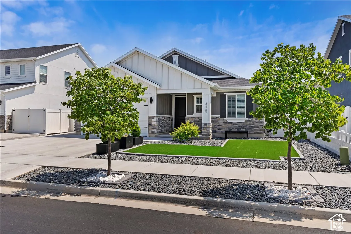 Modern exterior featuring a prominent front porch, stone veneer accents, and a low-maintenance landscape with artificial turf