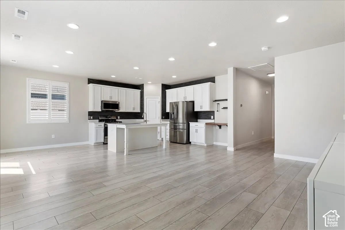 Open-concept living area featuring wood-finish flooring, recessed lighting, and white plantation shutters