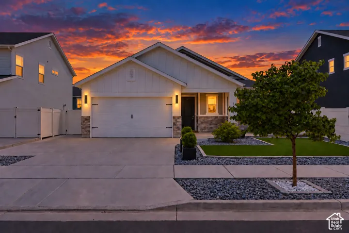 Siding exterior with stone accents, attached garage, concrete driveway, and front landscaping with decorative rock and artificial turf