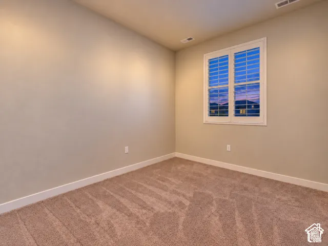 Single window with white plantation shutters, neutral-toned walls, and plush carpeting