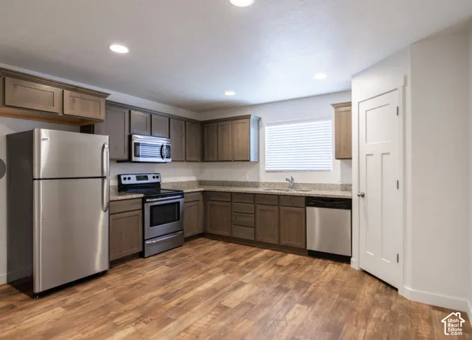 Kitchen featuring wood-finish flooring, recessed lighting, stainless steel appliances, wood cabinetry, and speckled countertops