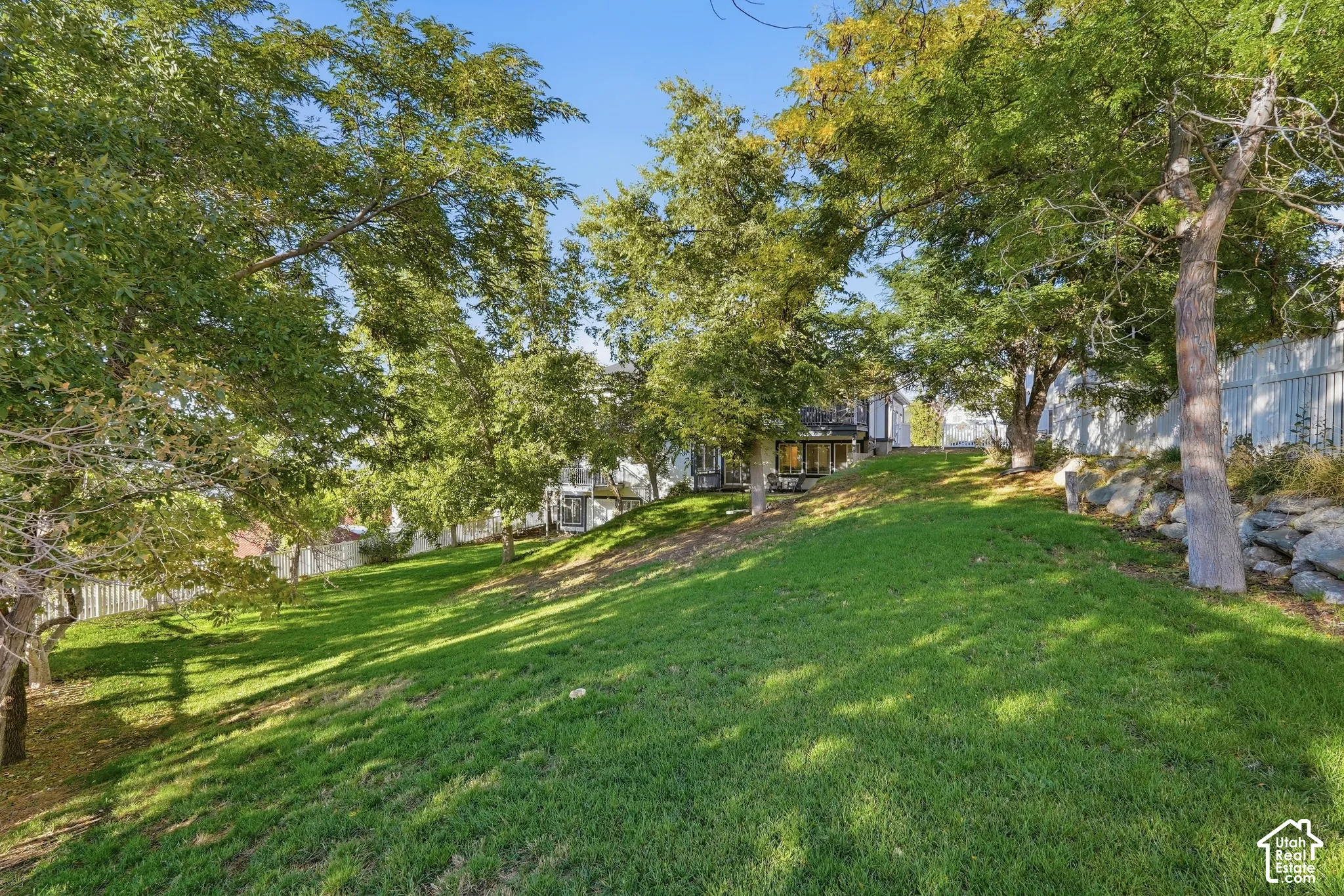 Sloping lawn with mature trees and stone retaining wall