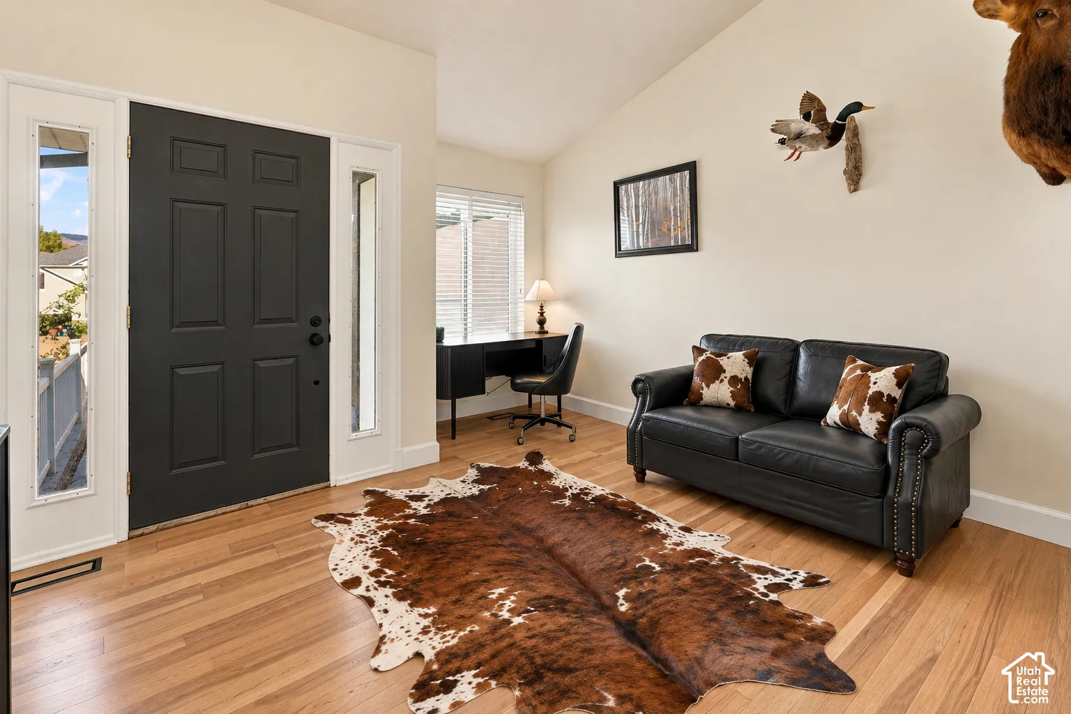 Entry foyer featuring a paneled door with sidelights, wood-finish flooring, and vaulted ceilings