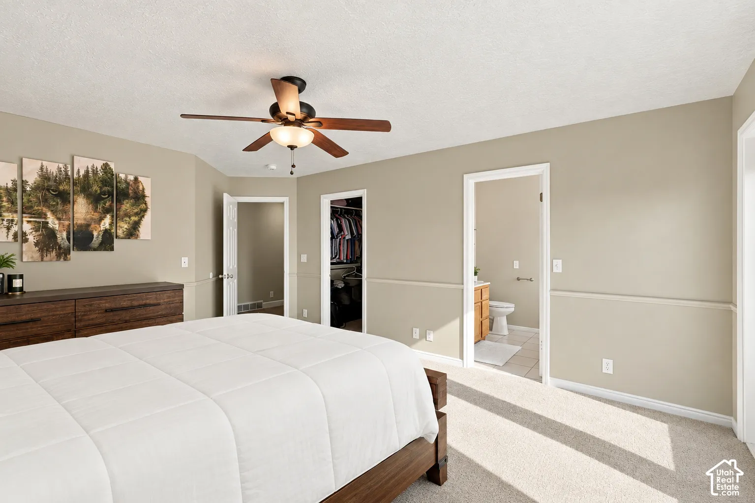 Neutral-toned walls with chair rail molding, carpeted flooring, and a ceiling fan with integrated lighting