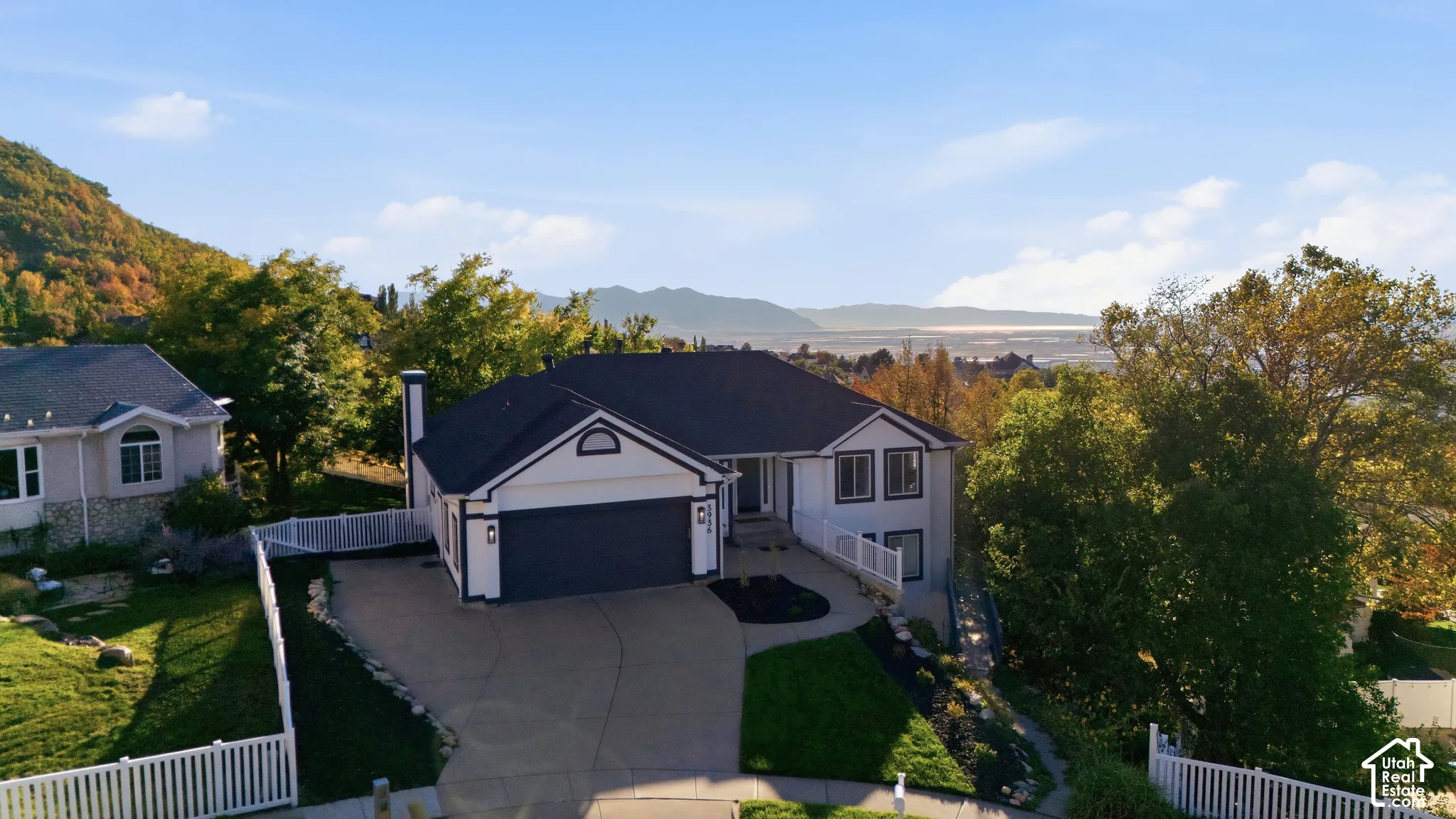 Two-story residence with a two-car garage, white picket fencing, and mature landscaping