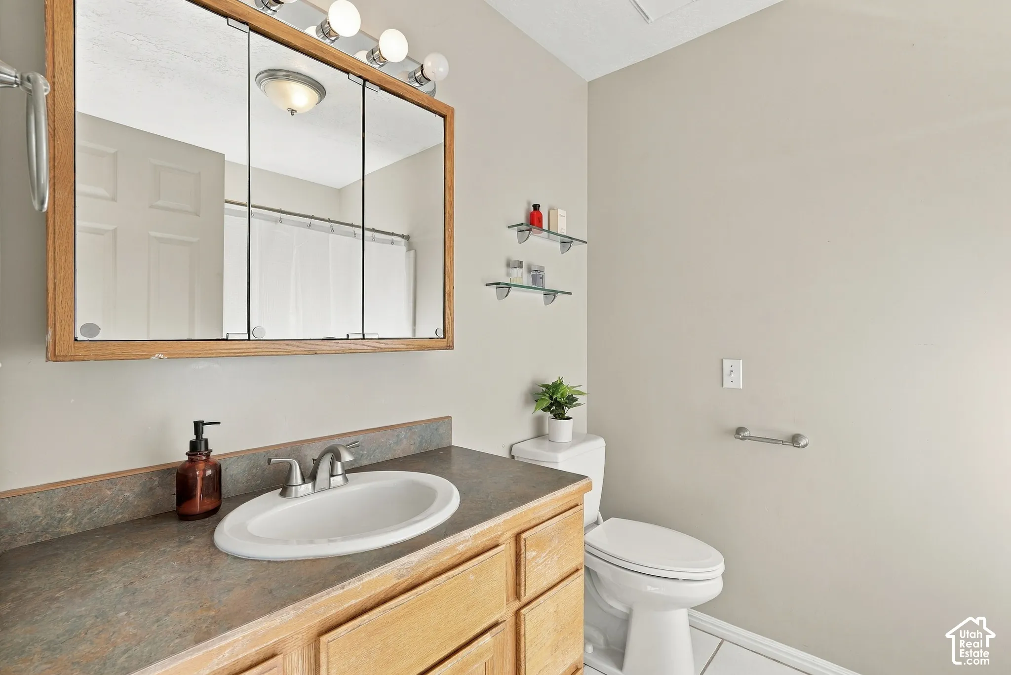 Bathroom featuring a wood-finish vanity with an integrated sink and a neutral-toned countertop