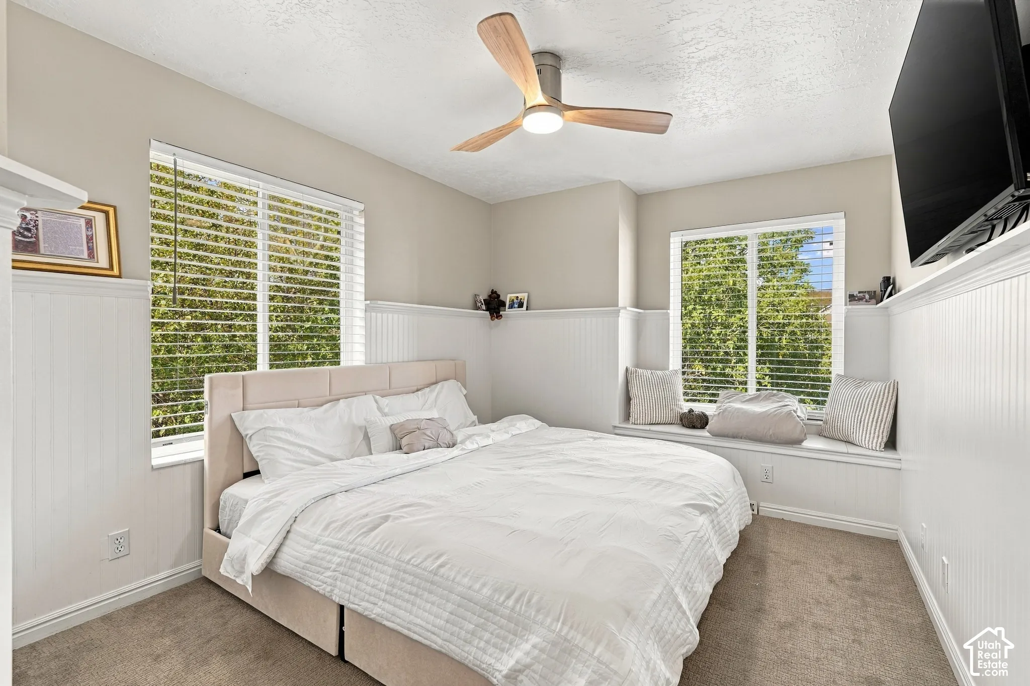 Wainscoting paneling, wood-tone ceiling fan, plush carpeting, and built-in window seating