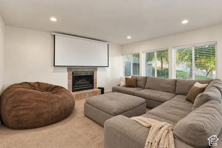 Integrated projection screen, tiled fireplace with black insert, recessed lighting, and multiple windows with blinds