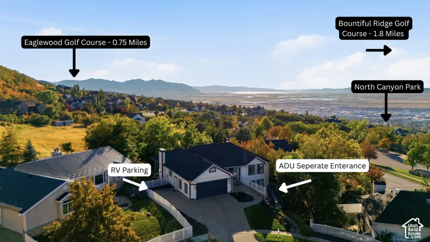 Stunning elevated property showcasing a modern residence with a dark-finished roof and attached garage, positioned on expansive grounds with mature landscaping