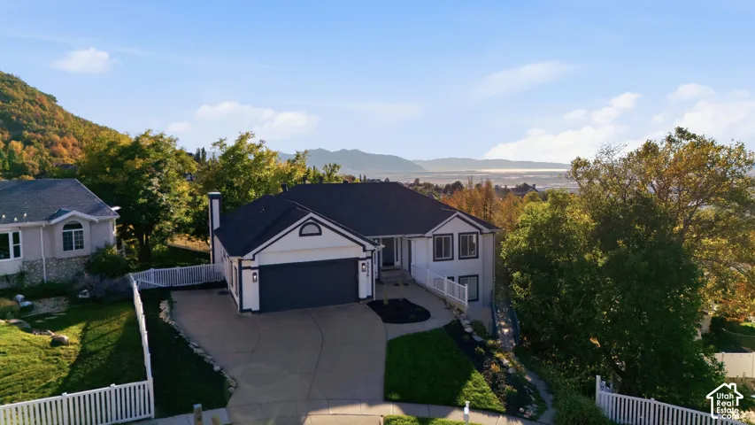 Two-story residence with a two-car garage, white picket fencing, and mature landscaping