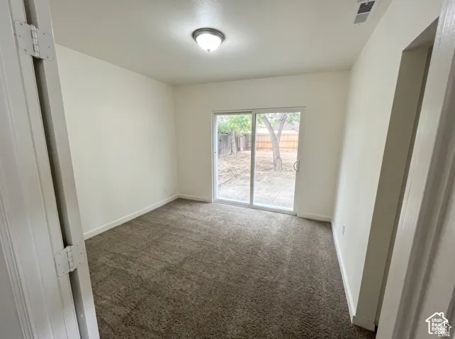 Neutral-toned carpet flooring, white walls, ceiling-mounted light fixture, and sliding glass door