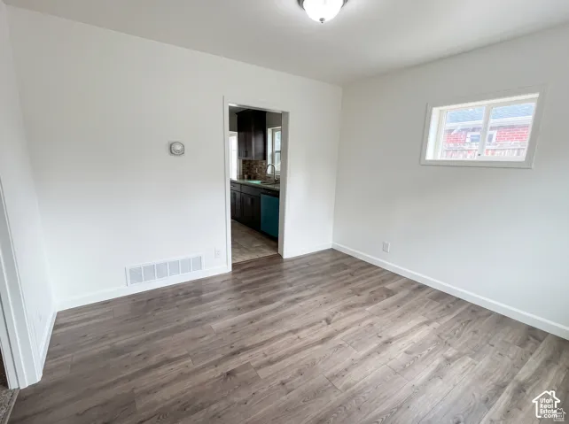 Wood-finish flooring, white walls, white trim, recessed lighting, and a single window
