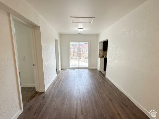 Wood-finish flooring throughout, bright white walls, and a sliding glass door providing access to the exterior