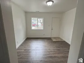 Wood-finish flooring, white walls, and a window with white trim