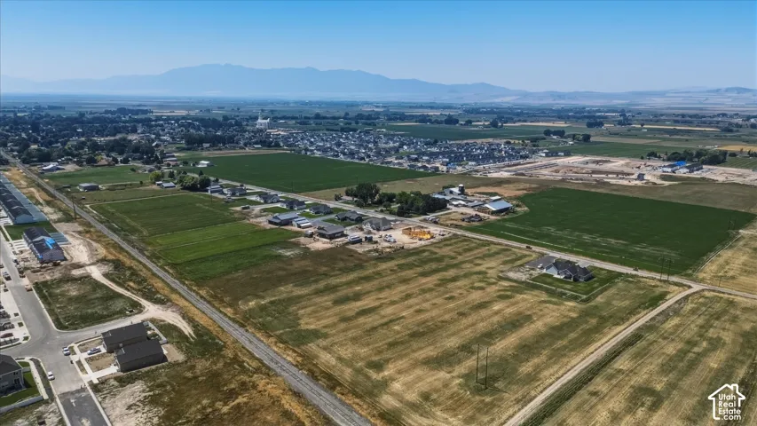 Expansive land parcel featuring existing residential structures and agricultural fields with distant mountain scenery