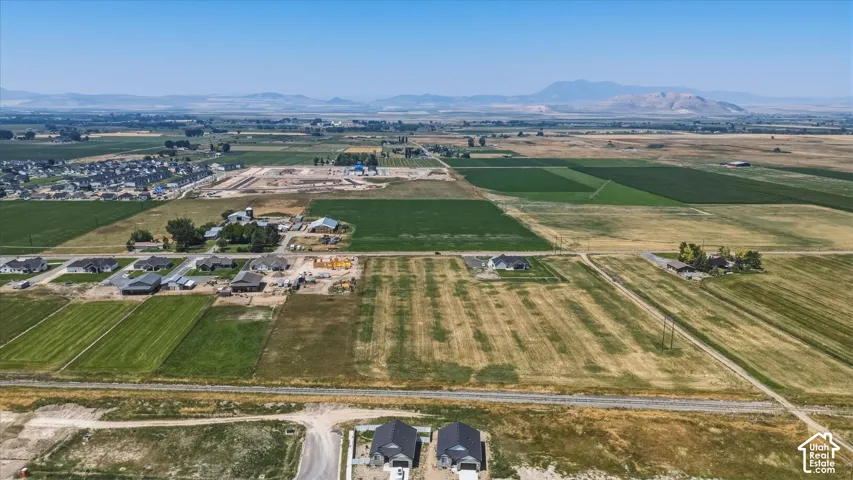 Expansive rural landscape with residential development, agricultural fields, and distant mountains