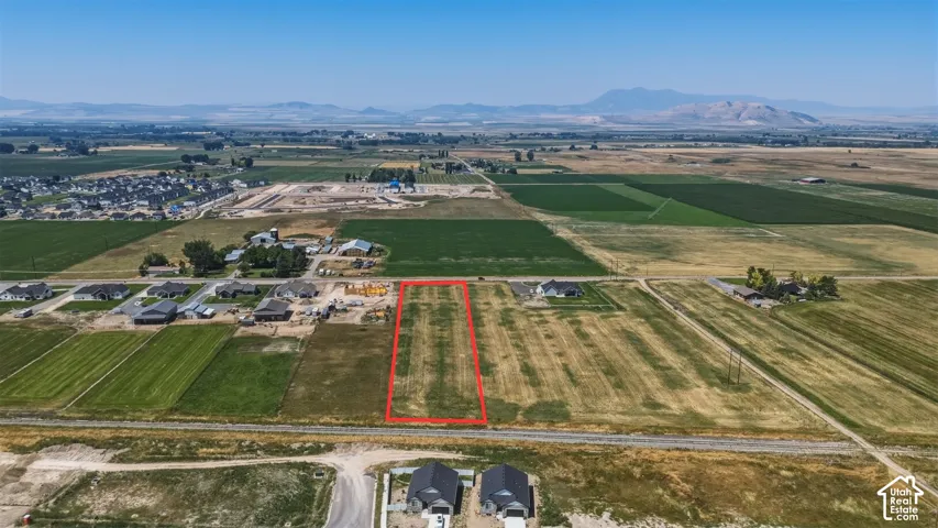 Expansive land parcel with surrounding agricultural fields, residential developments, and distant mountains