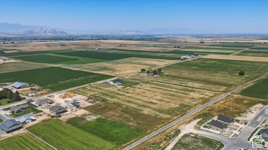 Expansive agricultural land with mountain backdrop, surrounded by developed residential areas