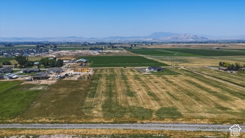 Expansive agricultural land with distant mountain backdrops and established residential areas nearby